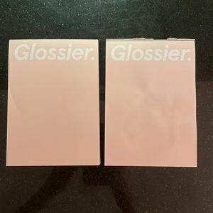 Two Glossier notepads